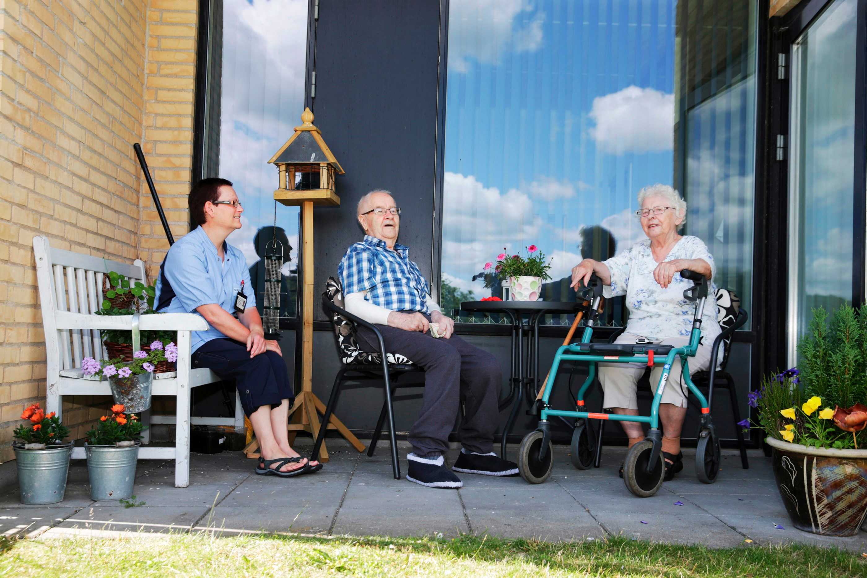 To beboere på Æblelunden hygger på deres terrasse med personale